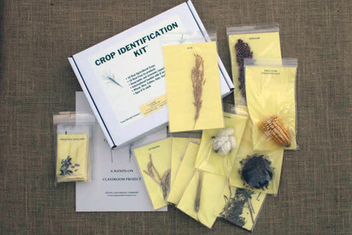 An educational crop identification kit with various packaged seeds and samples spread out on a table, along with a guidebook.