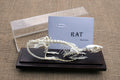 A real rat skeleton mounted on a wooden base with a clear acrylic cover, next to a note card with the word 'RAT' on it.